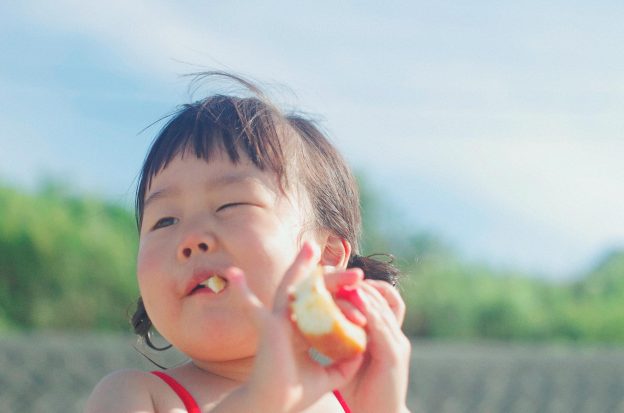 close up photography of a girl eating bread